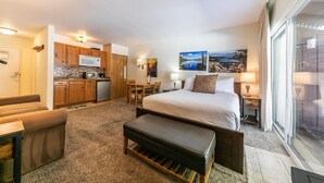 A hotel room with a bed, a desk, a kitchenette, and a view of a lake. - 212 Bldg B 1 Bedroom Condo (Truckee)