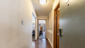 A hallway with wooden flooring, a door with a silver handle, and a light fixture on the ceiling. - 222 Bldg B 1 Bedroom Condo (Truckee)