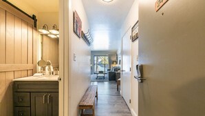 A hallway with a wooden bench, a kitchen area, and a dining table. - 245 Bldg C 1 Bedroom Condo (Truckee)