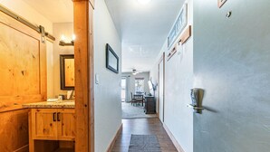 A hallway with wooden cabinets, a kitchen area, and a dining table. - 243 Bldg C 1 Bedroom Condo (Truckee)