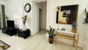 Una sala de estar moderna con un televisor de pantalla plana, un reloj, un cuadro y un banco.