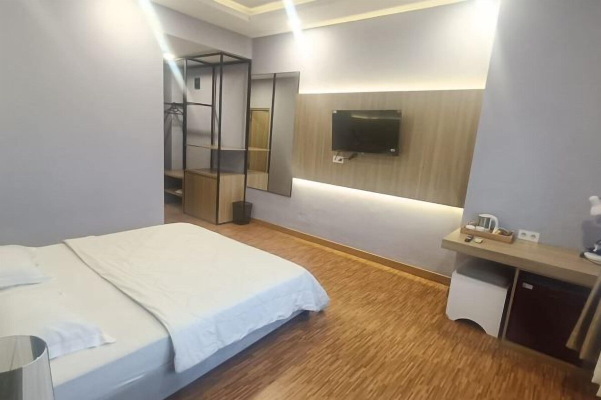 Une chambre d’hôtel comprenant un lit, une table de chevet, un miroir, une télévision et une armoire.