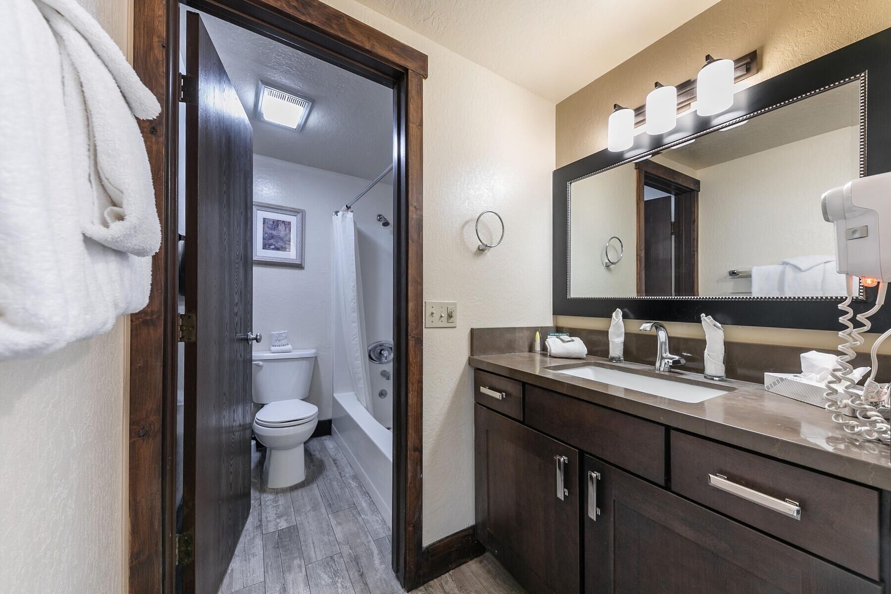 A bathroom with a dark wooden vanity, a large mirror, and a shower area.