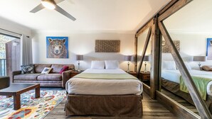 Een ruime slaapkamer met een groot bed, een sofa, een bijzettafeltje en een plafondventilator.