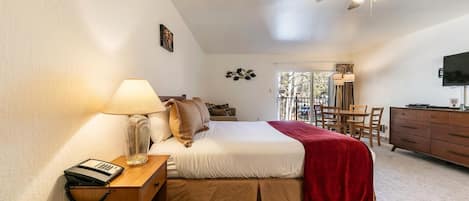 A bedroom with a bed, bedside table, lamp, and a ceiling fan.