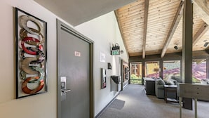 Un couloir avec une porte portant le numéro 217, une œuvre d’art abstraite encadrée, une horloge numérique et un coin salon offrant une vue sur l’extérieur.