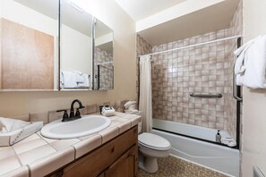 Een moderne badkamer met een wastafel, toilet en bad.