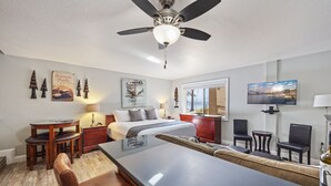 A modern hotel room with a bed, a dining table, a TV, and a ceiling fan. - 125 Bldg B Condo (Truckee)