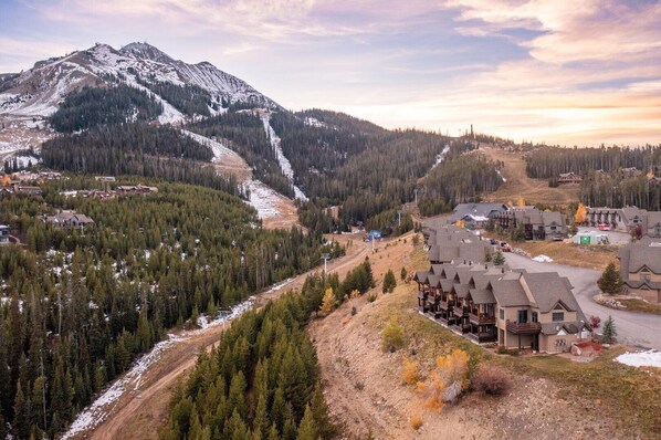 A mountain resort with a ski lift, wooden buildings, and a snow-covered landscape.