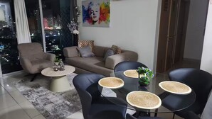 Ein modernes Wohnzimmer mit einer Couch, Sesseln, einem Couchtisch und einem Esstisch mit Platzsets.