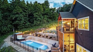 Une maison à deux étages avec une piscine, un espace salon extérieur et une terrasse.
