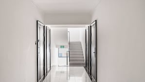 A clean, modern hallway with a marble floor, leading to a staircase and an emergency exit sign. - Modern 1-bedroom Apartment in Vibrant Westlands, Nairobi (Nairobi)