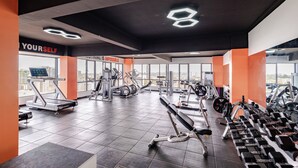 A modern gym with various exercise equipment, motivational wall quotes, and large windows offering city views. - Modern 1-bedroom Apartment in Vibrant Westlands, Nairobi (Nairobi)