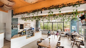 A modern cafe with wooden tables and chairs, a counter with beverages, and large windows allowing natural light. - Modern 1-bedroom Apartment in Vibrant Westlands, Nairobi (Nairobi)