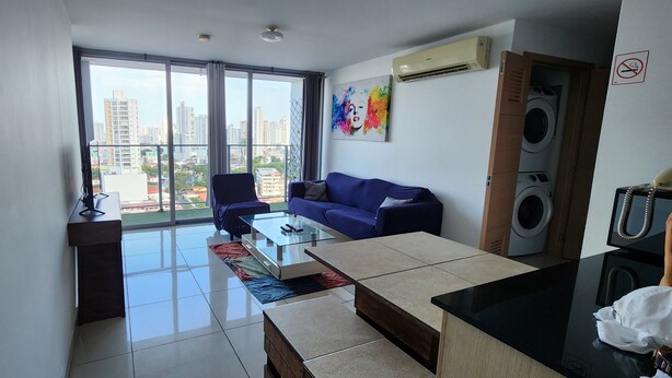 Un apartamento moderno con balcón, sofá, mesa de centro y lavadora.