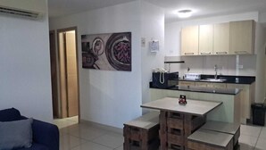 Un espacio habitable compacto con kitchenette, una mesa de comedor y un sofá.