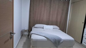 Un dormitorio con cama, mesita de noche y armario.