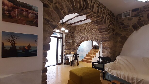Um interior rústico com paredes de pedra, espaço de refeições e um sofá.