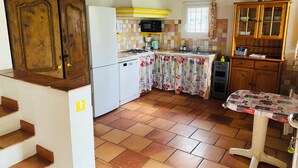 A kitchen with a tiled backsplash, wooden cabinets, a microwave, and a sink.