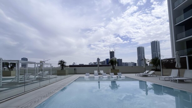Une piscine sur le toit, dotée de chaises longues et d’une rambarde en verre.