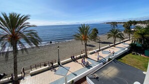 Eine Uferpromenade mit Palmen, einem gepflasterten Gehweg und Blick auf das Meer.