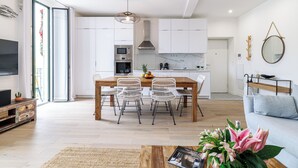 A modern living room with a wooden coffee table, a sofa, and a dining area with chairs and a table. - Sunlight Properties Archibald - Nice, 2 Beds, holiday rental, balcony & parking (Nice)