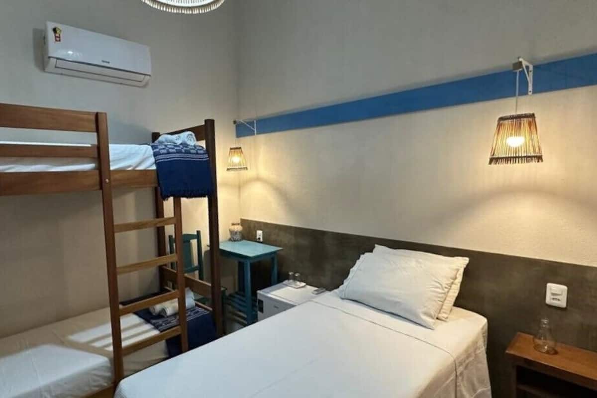 A room with bunk beds, a small table, a lamp, and an air conditioning unit.