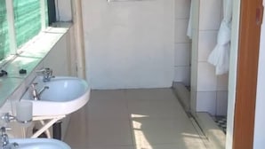 Un baño estrecho con dos lavamanos, una ducha y un perchero para toallas.