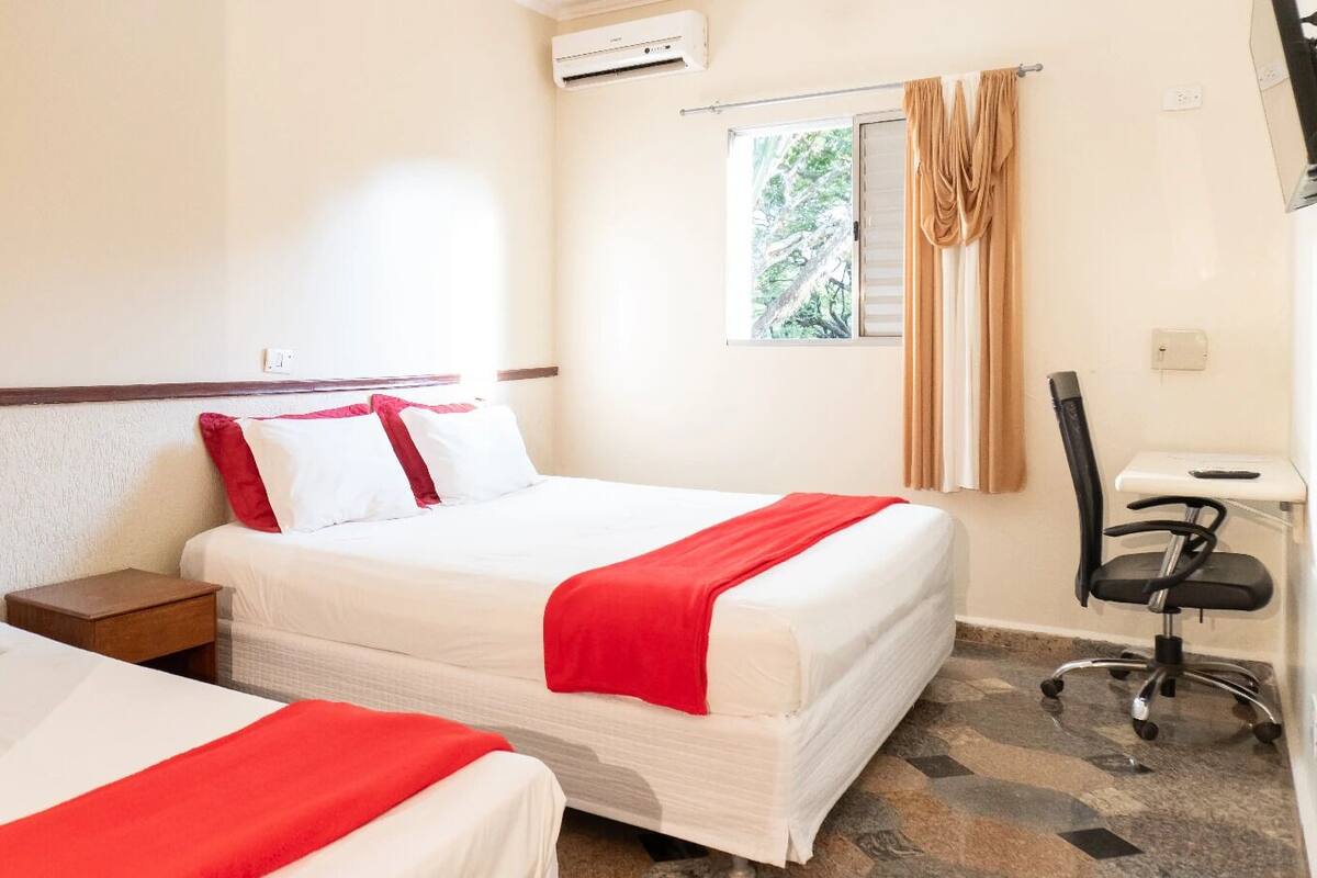 Ein Hotelzimmer mit zwei Betten, einem Schreibtisch und einem Stuhl.