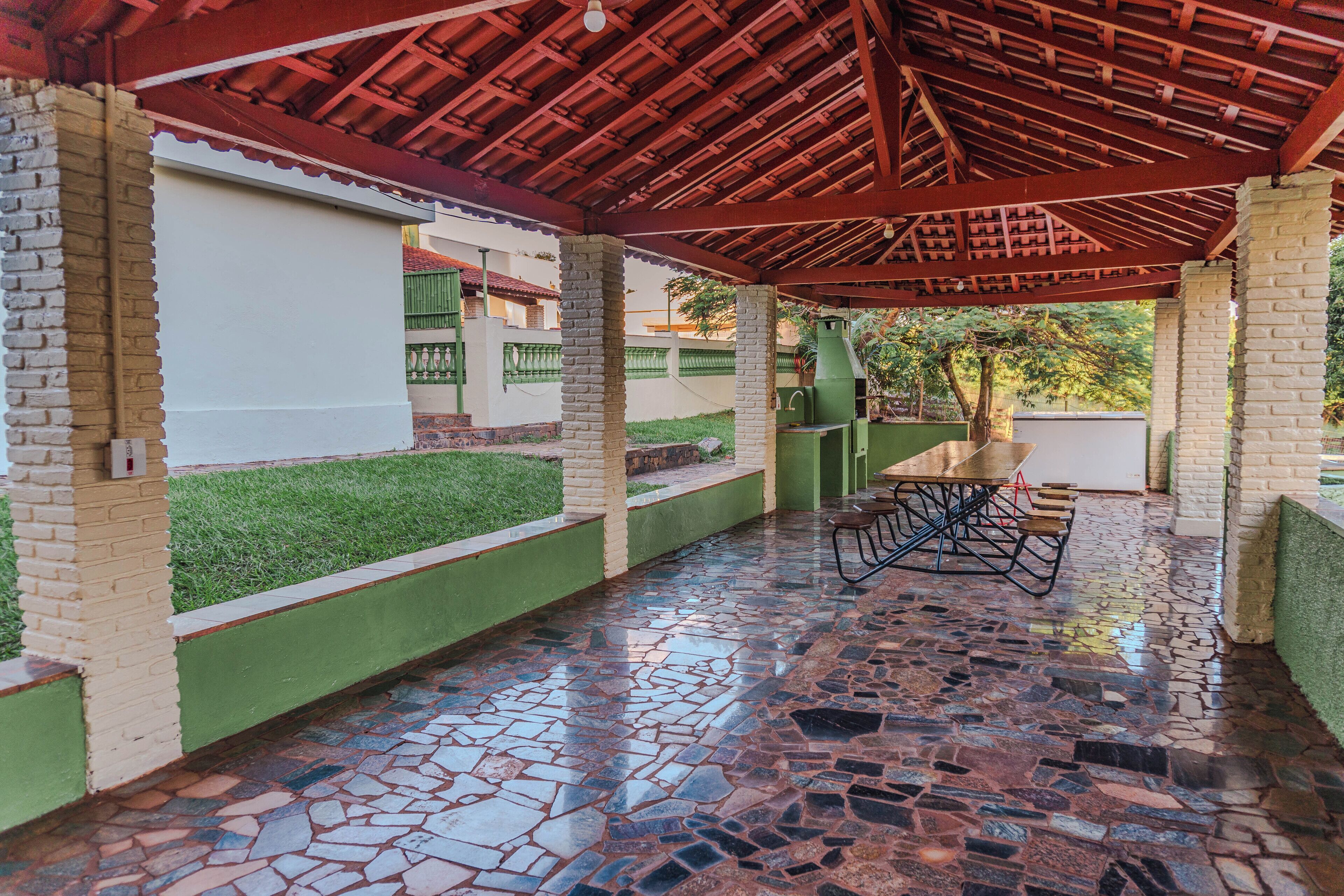 A covered patio area with a tiled floor, a table and chairs, and a green lawn.