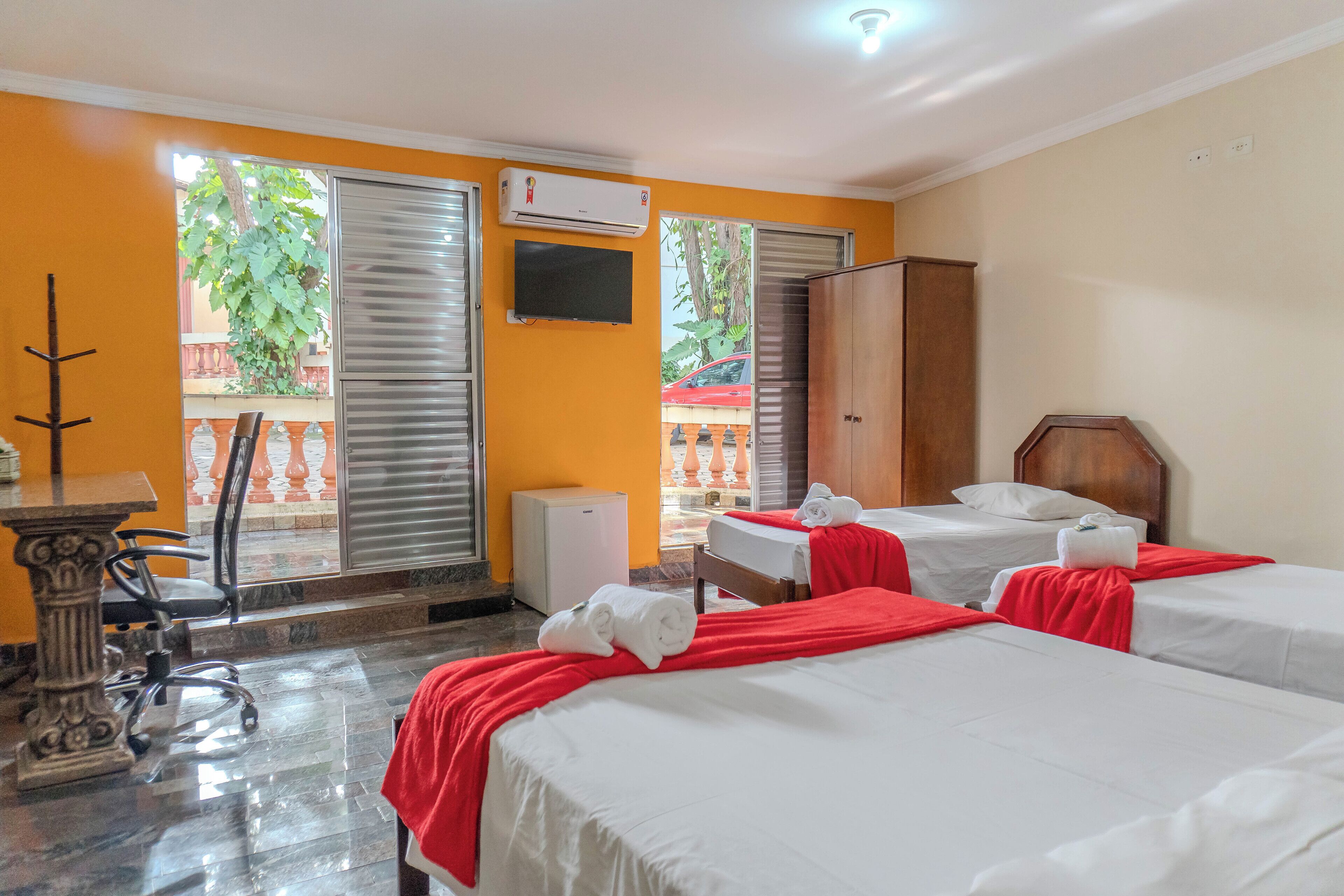 Una habitación de hotel con dos camas, un escritorio, una silla y una mesita.