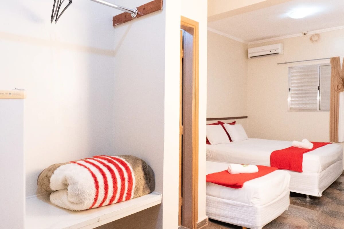 Ein Hotelzimmer mit Bett, einer kleinen Sitzecke und einem Fenster mit Jalousien.