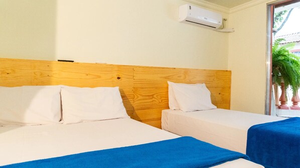 Een hotelkamer met twee bedden, een houten hoofdbord, wit beddengoed en een blauwe deken.