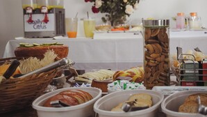 Een ontbijtbuffet met diverse etenswaren, zoals brood, gebak en een sapautomaat.