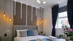 Ein modernes Hotelzimmer mit einem großen Bett, Nachttischen, einem Schreibtisch und Blick auf die Stadt.