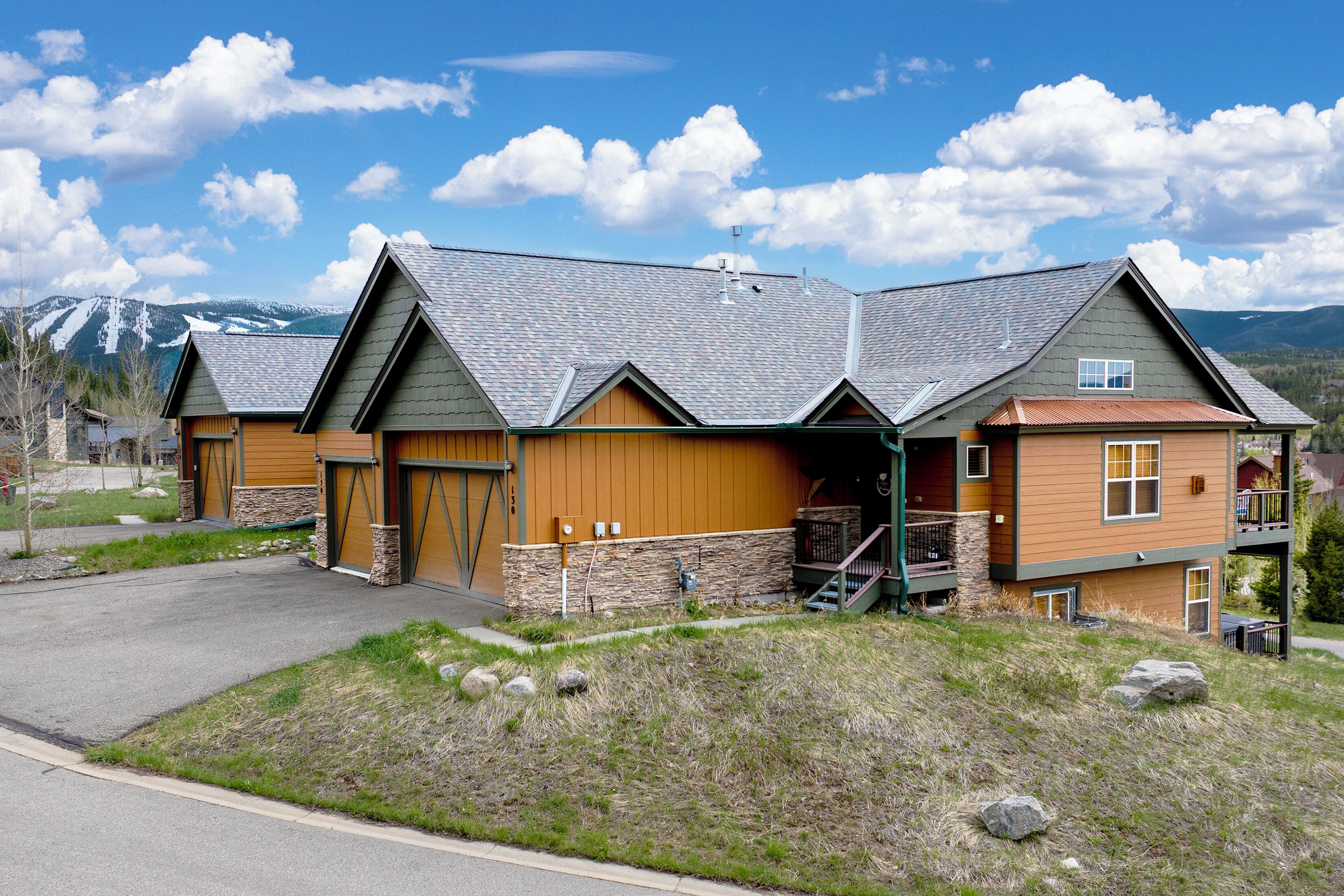 A two-story building with a stone foundation, wooden siding, and a sloped roof.