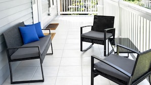A covered porch with a ceiling fan, a bench with cushions, and two chairs. - World Cup House ATL (Atlanta)