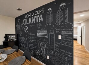 A room with a large wall mural featuring the World Cup and Atlanta, USA, with a dining area in the foreground.
