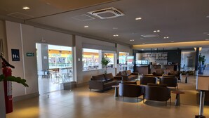 A spacious lobby with leather sofas, a reception desk, and a view of the outdoor dining area. - Hospede-se no Solar das Águas (Olímpia)