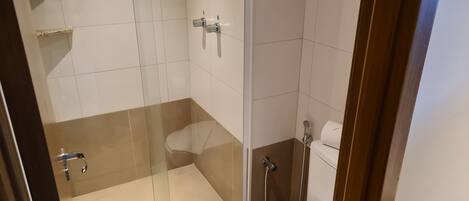 Une douche en verre avec des toilettes et une serviette.