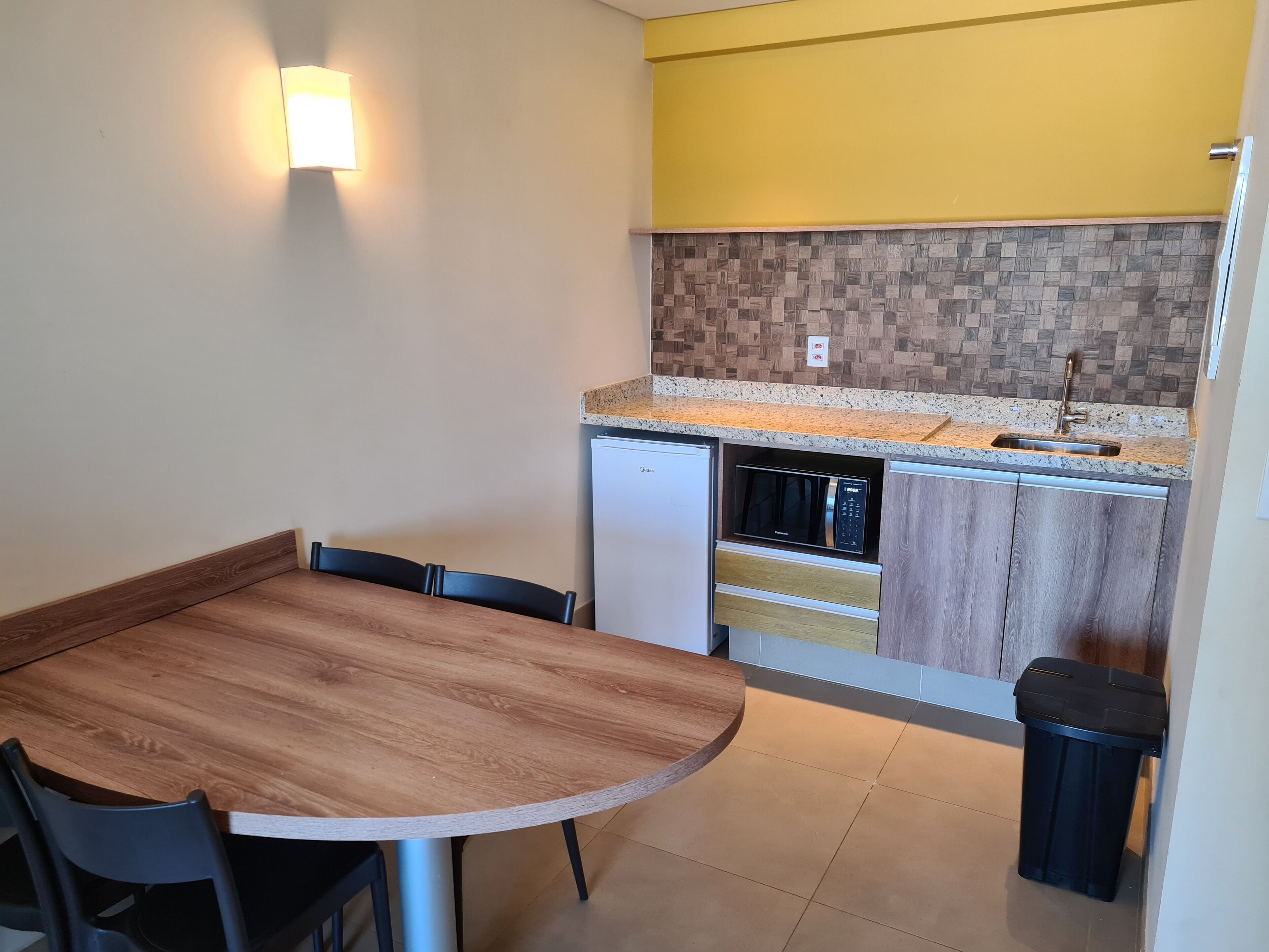 A compact kitchen with a microwave, sink, and a small refrigerator.
