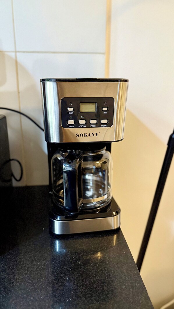 Una cafetera de acero inoxidable con pantalla digital y botones de control sobre una encimera de cocina.