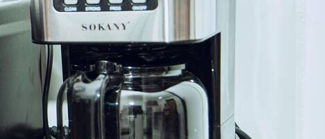 Una cafetera de acero inoxidable con pantalla digital y botones de control, ubicada sobre una encimera de cocina.