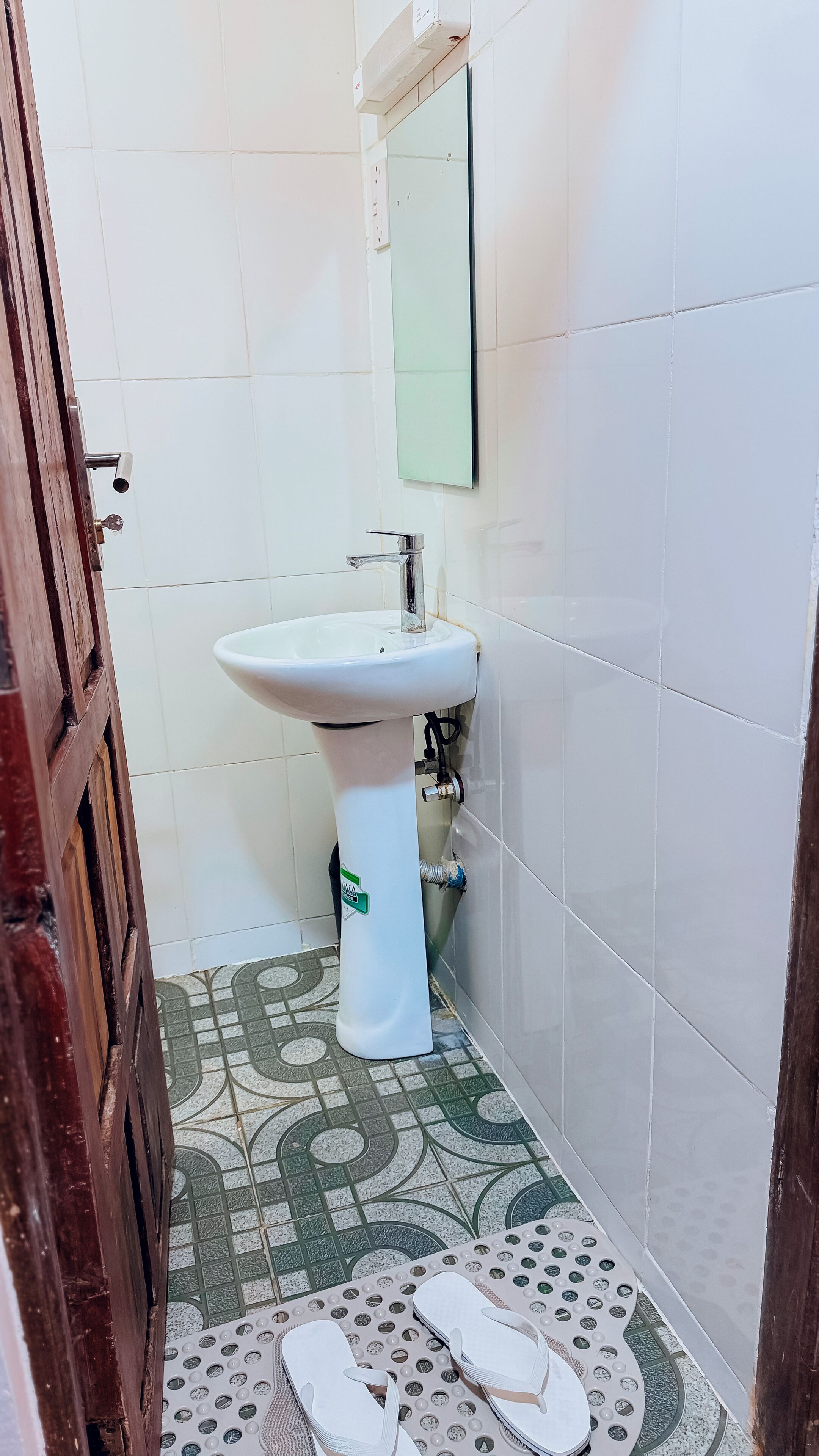 Un bagno con un lavandino bianco, uno specchio e un pavimento decorato.