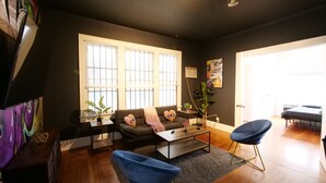 A modern living room with a dark wall, a sofa, a coffee table, and two blue chairs. - Miami style gem/central location (Miami)