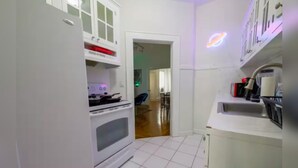 A kitchen with white cabinets, a stove, and a sink. There is a doorway leading to another room. - Miami style gem/central location (Miami)