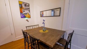 A dining area with a wooden table and chairs, a vase with flowers, and a colorful abstract painting on the wall. - Miami style gem/central location (Miami)