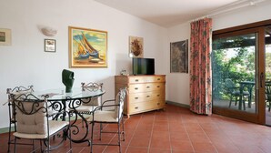 A dining area with a glass table and chairs, a wooden cabinet, and artwork on the walls.