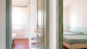 A room with a bed, a bedside table, and a window with curtains.