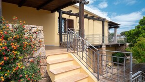 A stone staircase leading to a wooden deck with a metal railing.